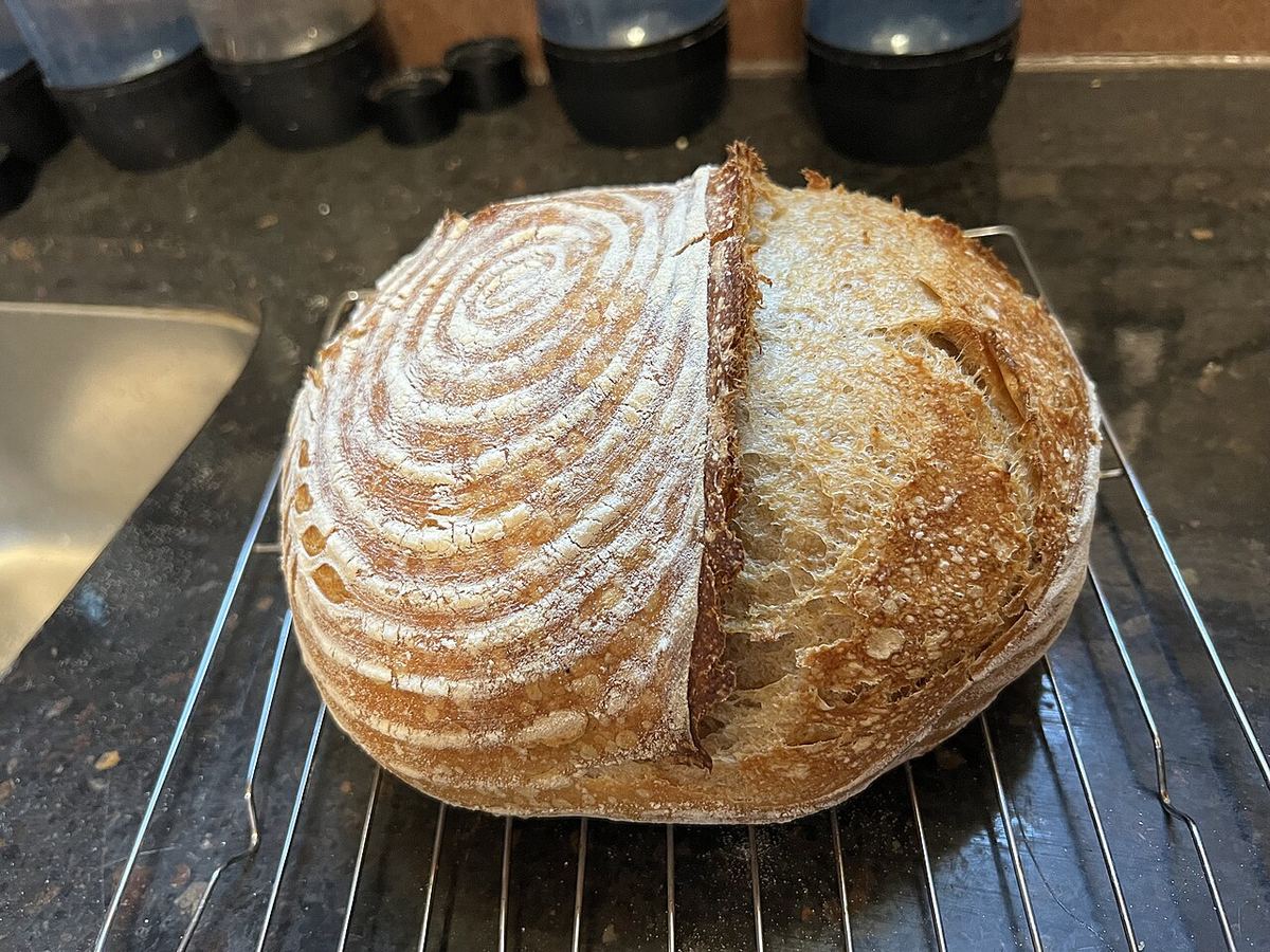 Miche de pain au levain farinée, grignée en épi et posée sur une grille