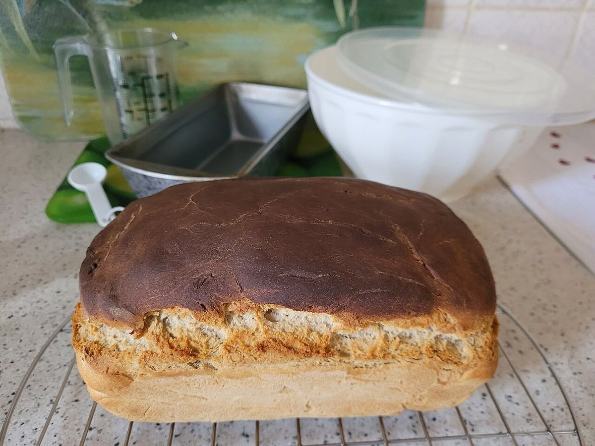 Pain maison sur une grille entouré d'ustensiles de cuisine