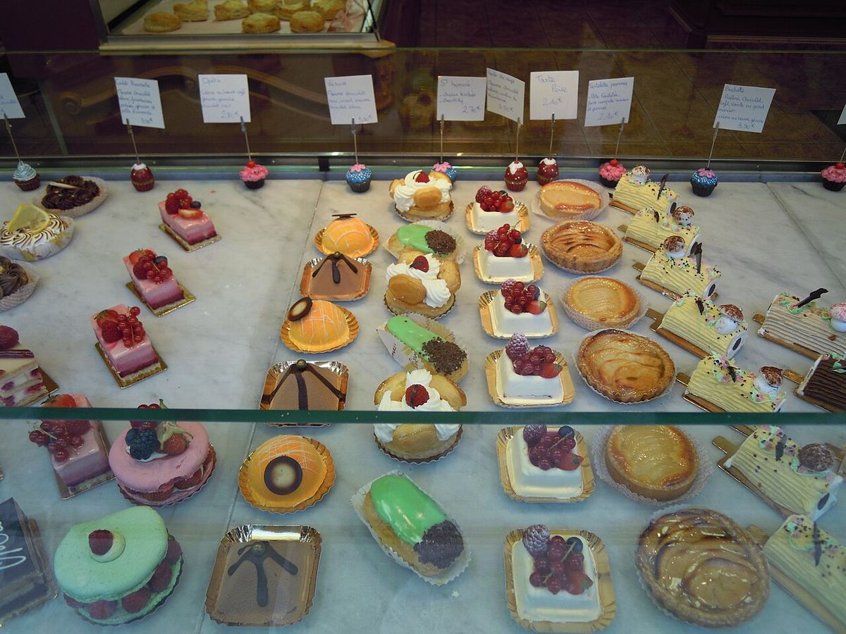 Vitrine de pâtisserie remplie de gâteaux individuels colorés